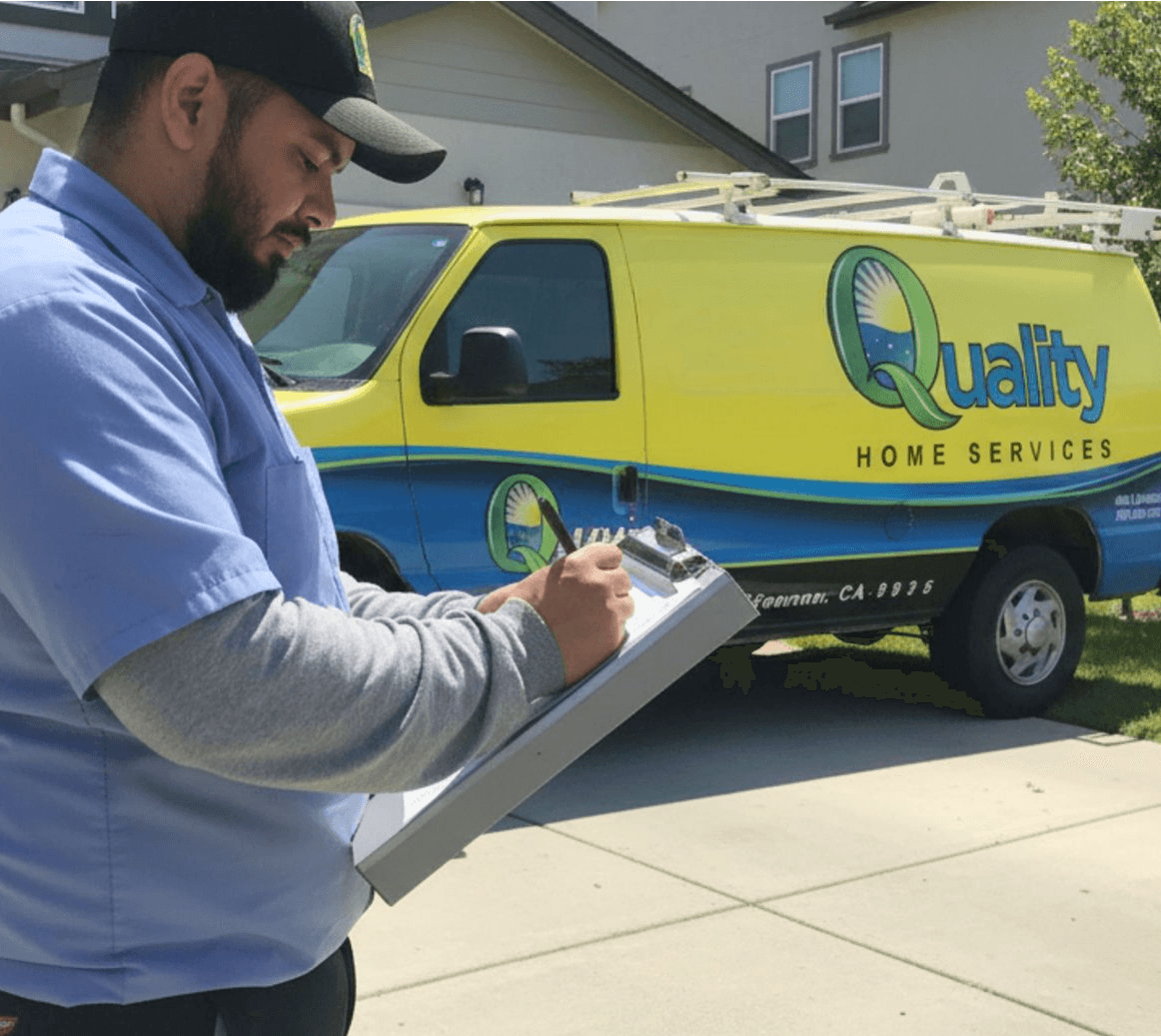 A technician in a blue uniform writes on a clipboard outside a house. A yellow service van with "Quality Home Services" is parked nearby.
