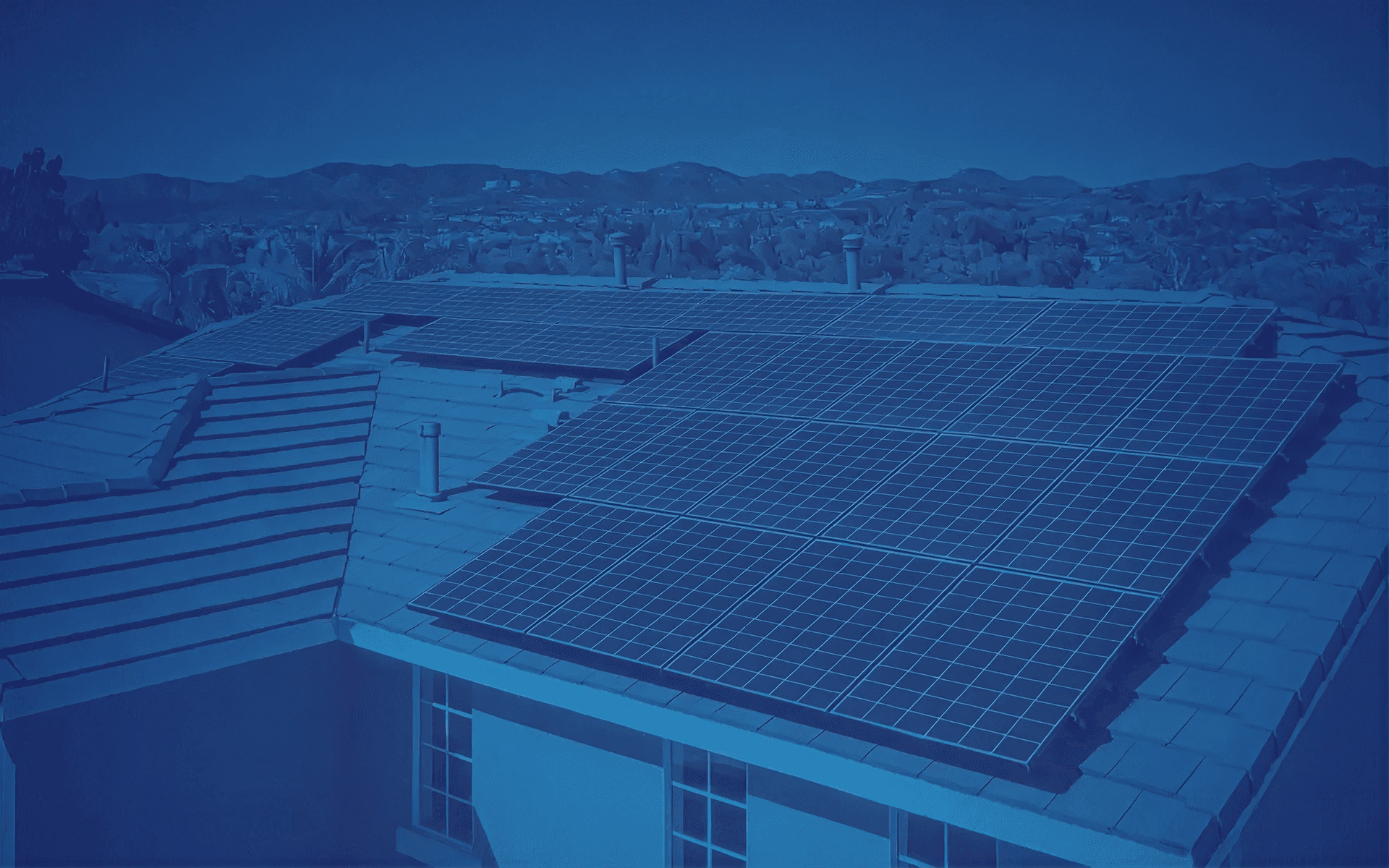 A roof topped with solar panels set against a clear sky and distant hills, conveying sustainability and eco-friendly energy use. The mood is serene.