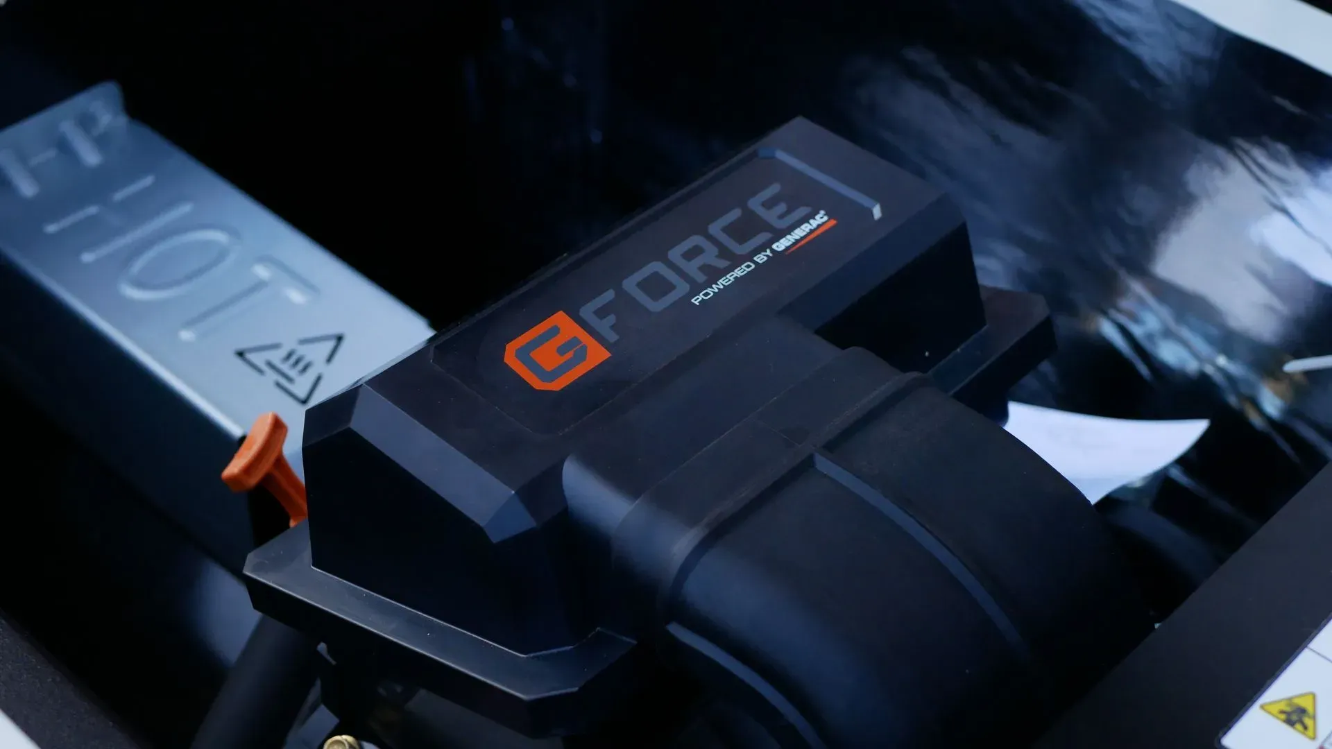 Close-up of a "G-Force" branded engine component in a dark setting. The sleek design and logos suggest high performance and advanced technology.